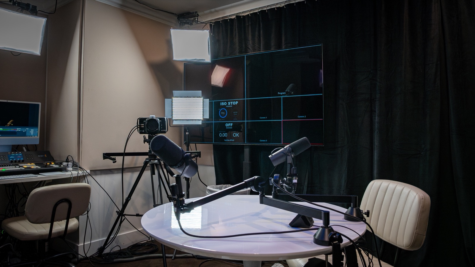 The Podcast Room, with microphones on booms around a table and cameras rigged